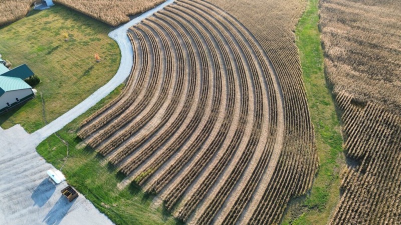 Aerial view of curved crop rows beside the warehouse
