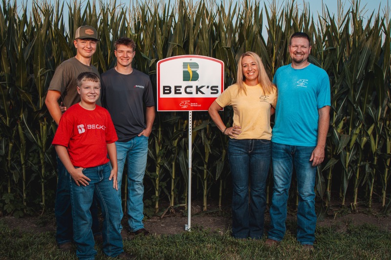 The Robinson family beside a Beck’s Hybrids and CR Seeds & Services sign in a cornfield