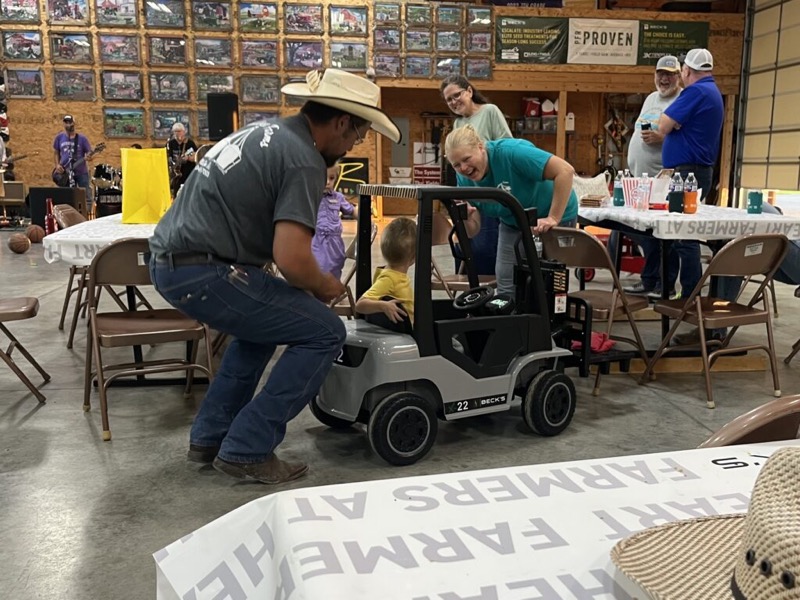 Kids riding a toy forklift at a customer event in the warehouse